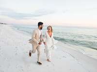 Bride and groom running on a beach