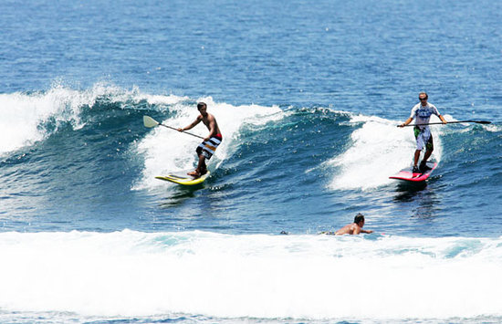 What is standing on a surfboard and paddling called