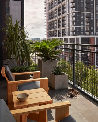 Image may contain Architecture Balcony Building Plant Chair Furniture Desk Table and City