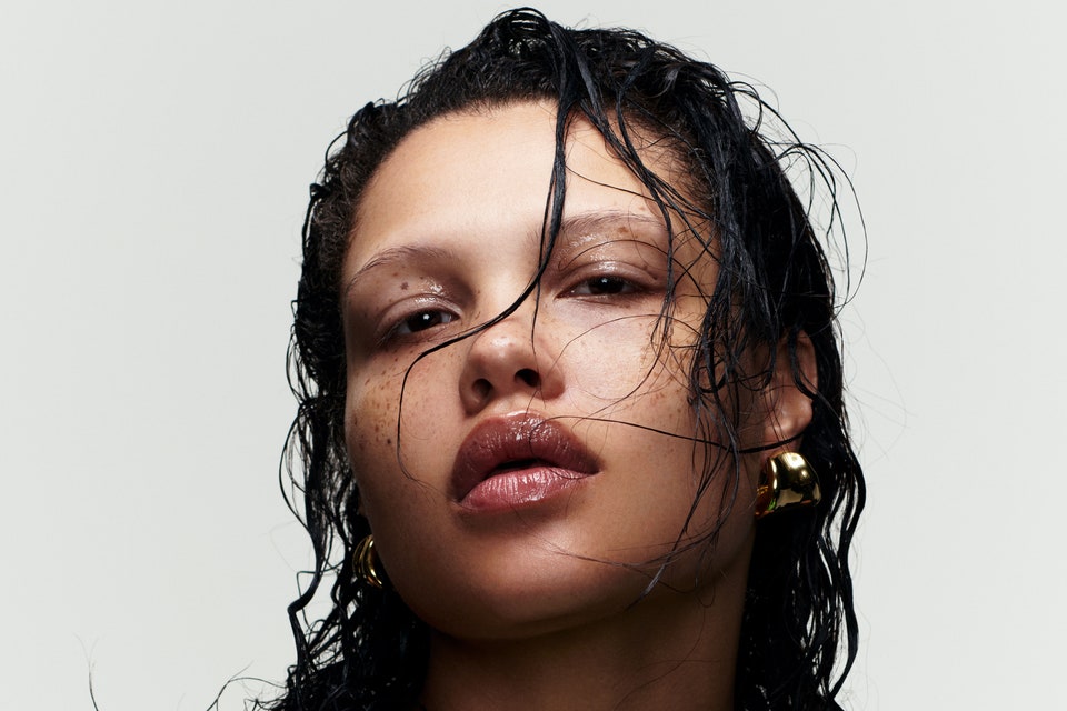 Model with stands of hair in her face wearing green top