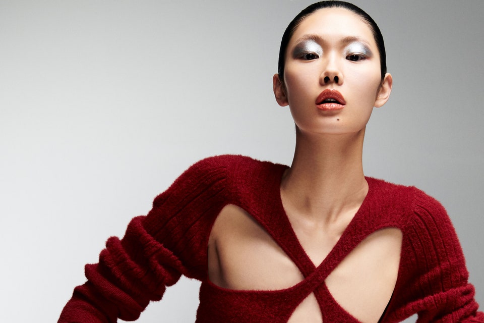 Model in red sweater dress against sliver background