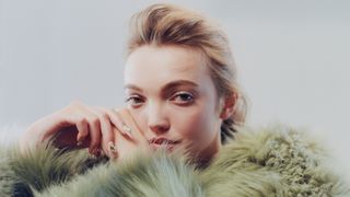 Model wearing green fur jacket on a soft blue background