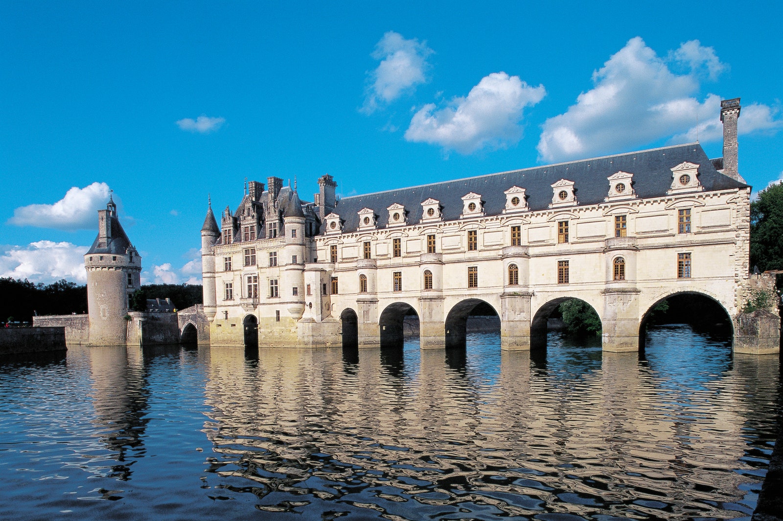 a castle in front of blue sky that extends over the water