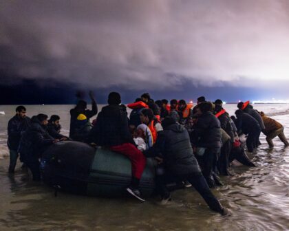 TOPSHOT - Migrants board a smuggler's inflatable dinghy in an attempt to cross the English