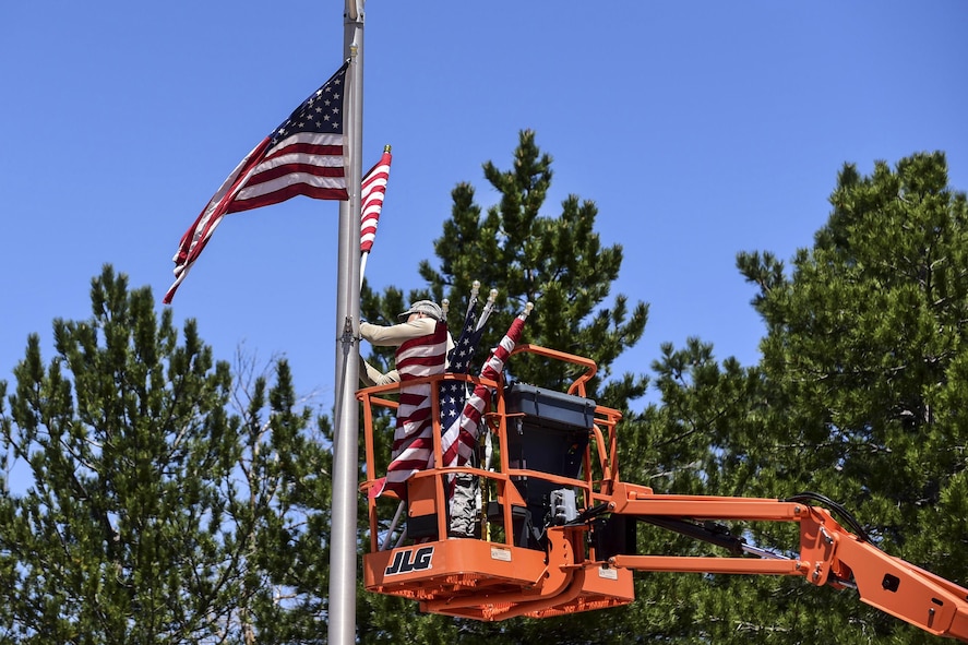 Air Force Staff Sgt. Steven Price attaching an American flag to a light pole.