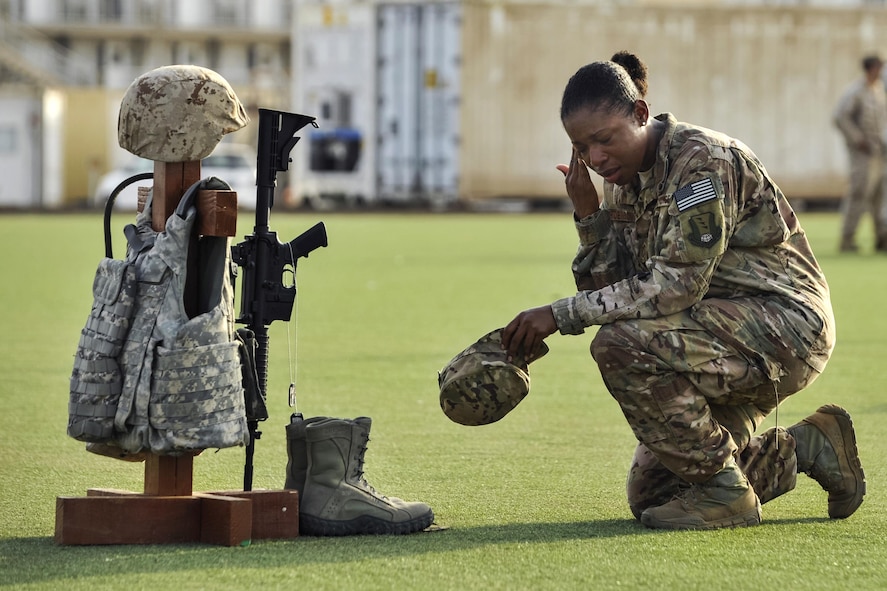 Air Force Master Sgt. Tiffany Robinson kneeling in front of a battlefield cross.