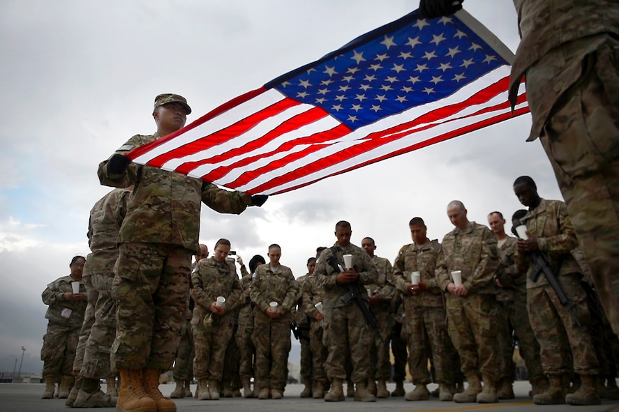 Air Force Senior Airman Jerick Encarnacion, left, holding a flag.