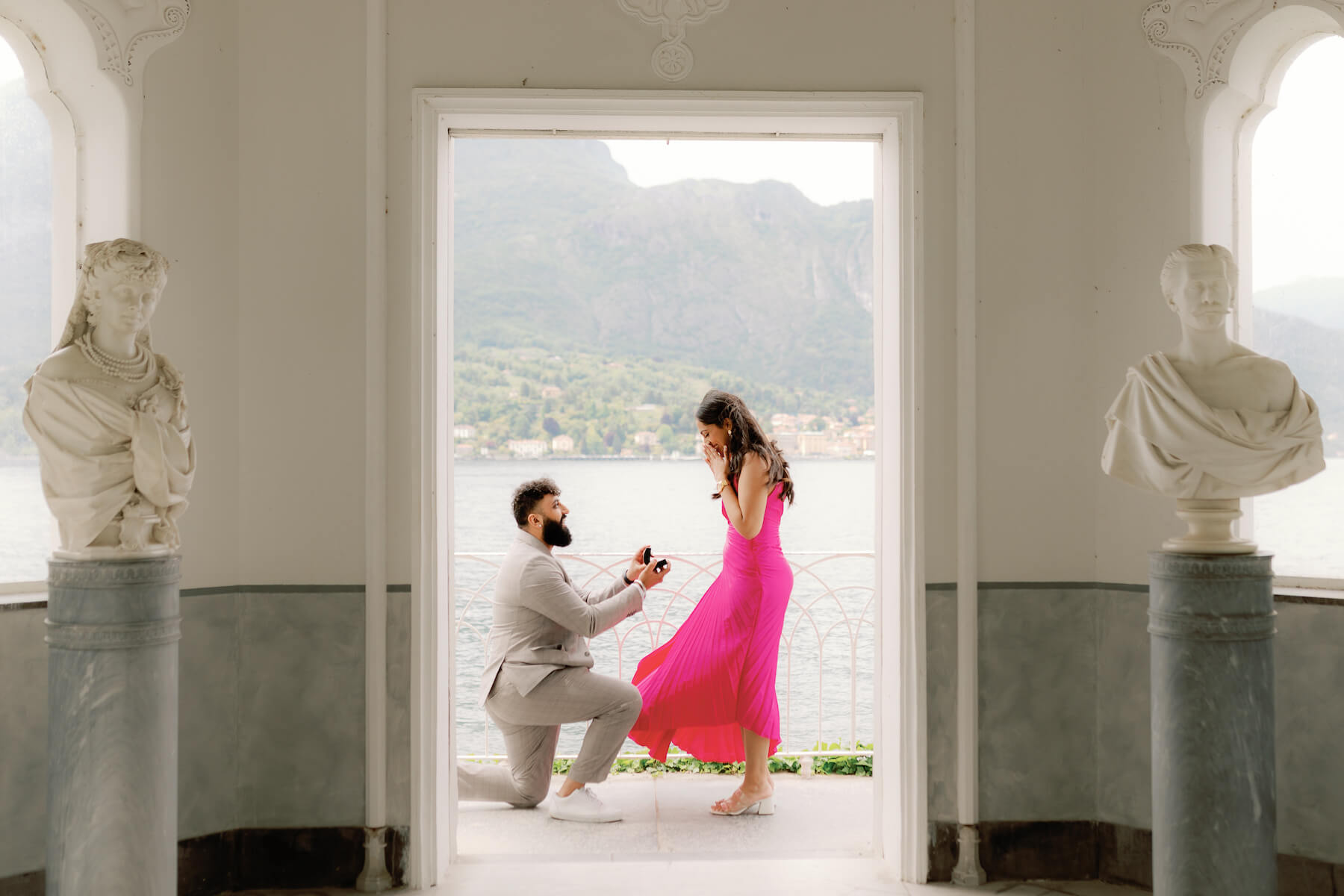 A couple holds each other standing on a balcony over the lake while on a surprise proposal photoshoot for Flytographer.