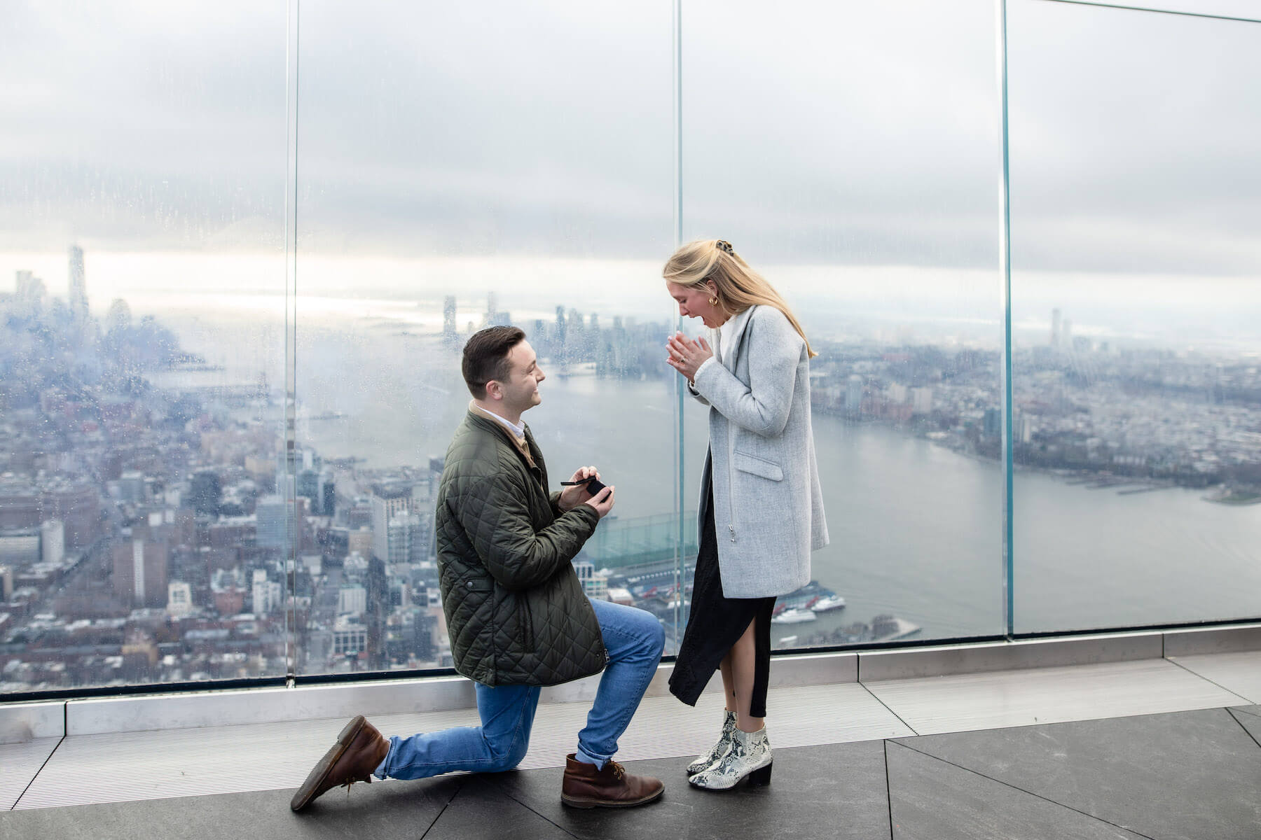 A man proposes to a woman on top of a rooftop building in New York City while on a proposal photoshoot with Flytographer.