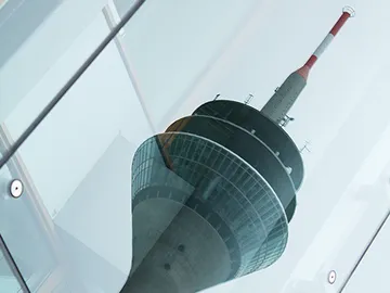 Ein Fernsehturm spiegelt sich auf Glas in leichter Nebel.