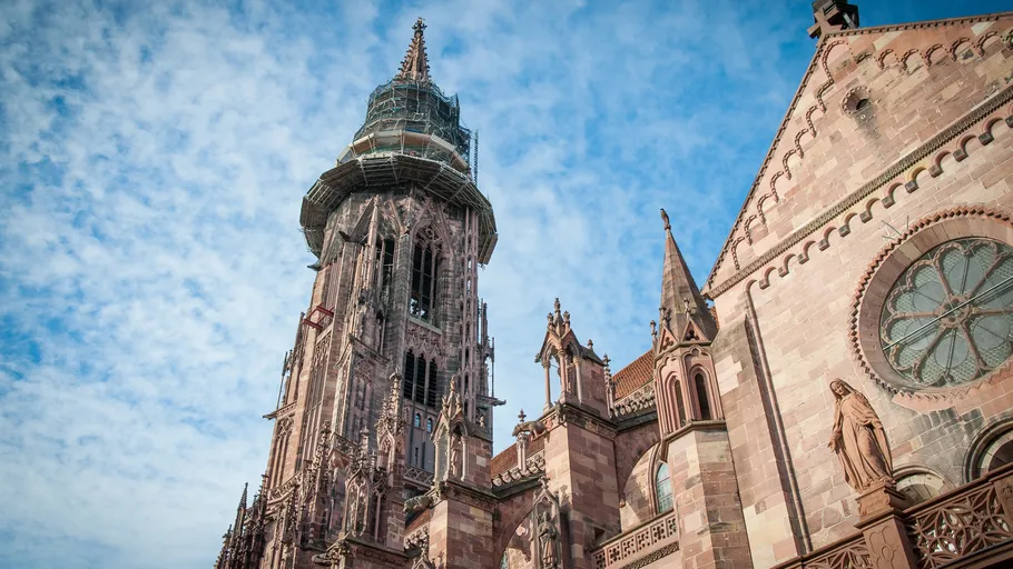 Hoher Kirchturm mit Baugerüst unter blauem Himmel.