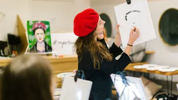 Eine künstlerische Frau malt mit einem Bleistift auf Papier.