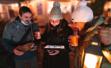 Drei Personen schauen gemeinsam auf ein Tablet bei Nacht.