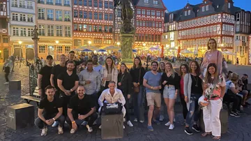 Gruppe von Personen posiert vor historischen Gebäuden abends.