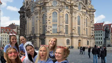 Gruppe von Frauen posiert fröhlich vor historischer Kirche.