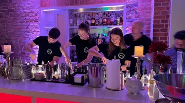 Bartender mixen Cocktails an einer beleuchteten Bar mit Getränken.