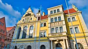 Gelbes Rathaus hat große Fenster und einen Uhrturm.