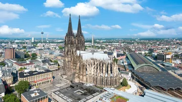 Kölner Dom überragt Stadt, umgeben von moderner Architektur.