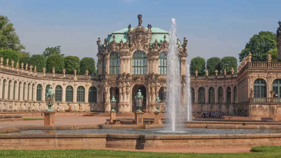 Brunnen sprudelt vor einem prunkvollen historischen Gebäude.