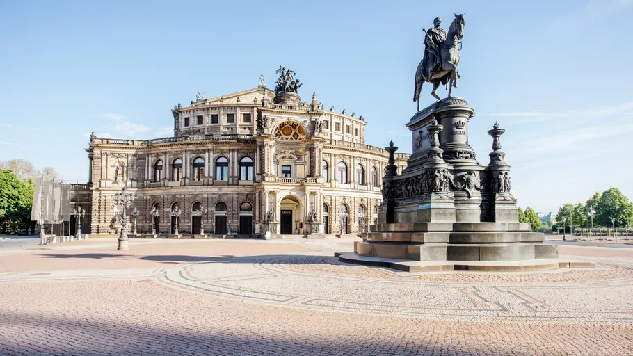 Historisches Gebäude mit Reiterstatue in sonnigem Platz.