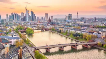 Moderne Stadtlandschaft, Fluss fließt, Sonnenuntergang im Hintergrund.