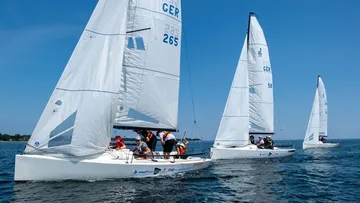 Segelboote fahren über Wasser, während Menschen segeln.