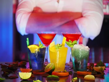 Bunte Cocktails stehen auf einem Tisch mit Früchten.