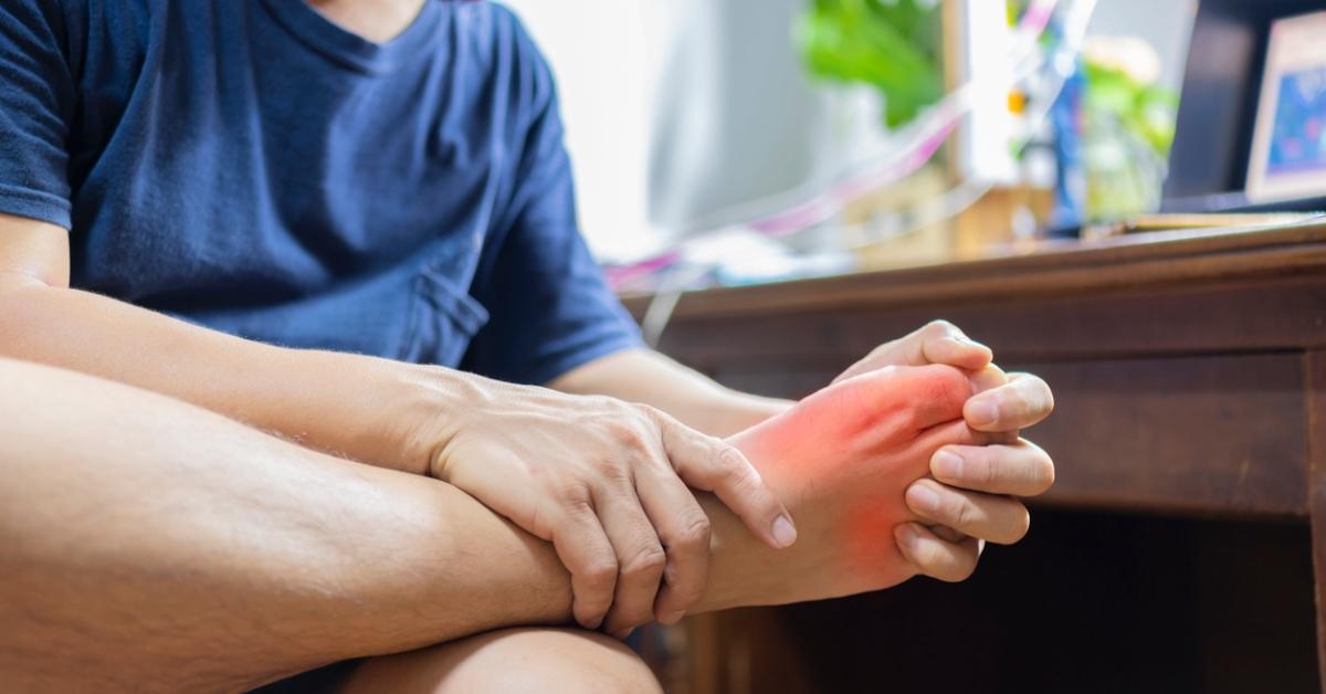 A man clutches his foot in pain. 