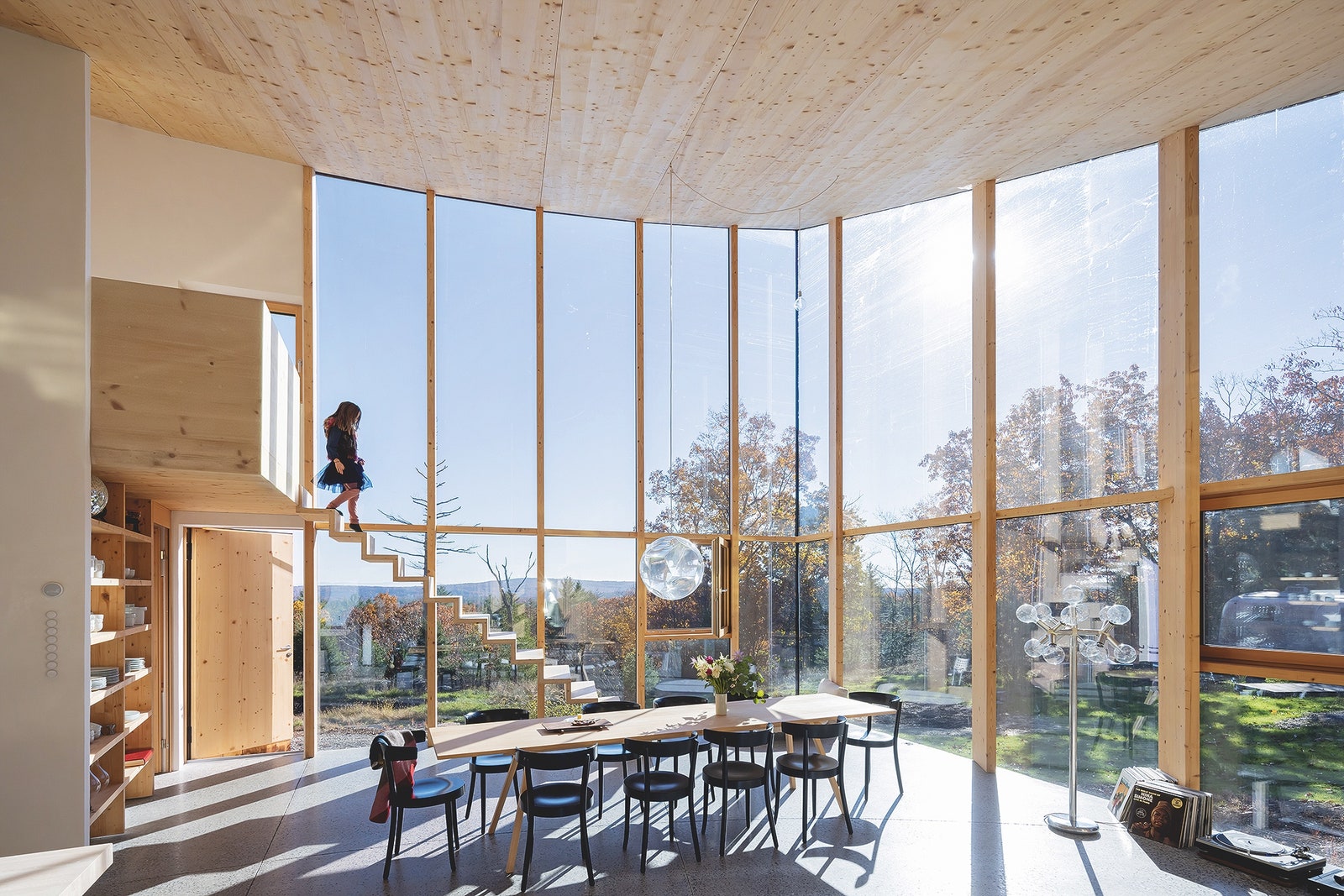 Gran sala con ventanas de suelo a techo y escalera de madera