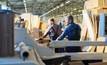 Two workers in a factory that practices waste reduction management.