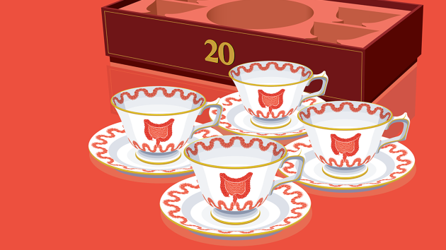 Teacups decorated with pictures of intestines, and a box in the background with ‘20’ on the front of it. 