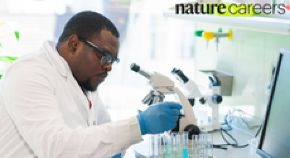 Scientist looking through microscope in lab