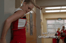 a cheerleader is leaning against a wall with guest starring amber riley on the bottom