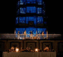 a group of people standing on a balcony in front of a building with a sign that says ' king ' on it