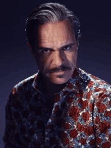 a man with a mustache wearing a floral shirt