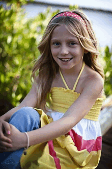 a young girl wearing a yellow top and a red headband