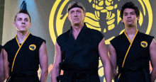 three men in karate uniforms are standing in front of a karate symbol