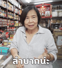 a woman in a striped shirt is standing in front of a counter with a sign that says ' a '