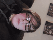 a young man wearing glasses is laying down on a couch