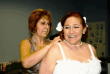 a woman helping another woman with her wedding dress