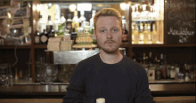 a man stands in front of a bar with bottles of alcohol and a sign that says ' hansen '