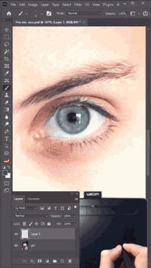 a person is editing a picture of a woman 's eye with a wacom tablet in the background