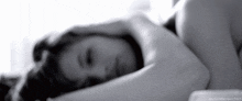 a black and white photo of a woman laying in bed with her eyes closed