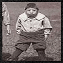 a black and white photo of a young boy standing on a field .