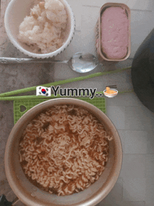 a bowl of noodles sits next to a bowl of rice a spoon and a can of ham