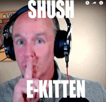 a man wearing headphones holds his finger to his lips and says " shush e-kitten "