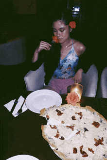 a woman sitting at a table eating a pizza