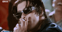 a man wearing sunglasses smoking a cigarette with eros written on the bottom