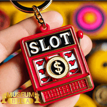 a person is holding a red slot machine keychain in their hand