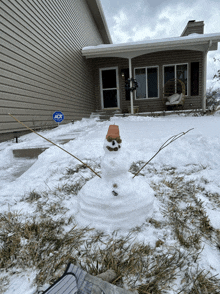 a snowman in front of a house with an adk sign in the background